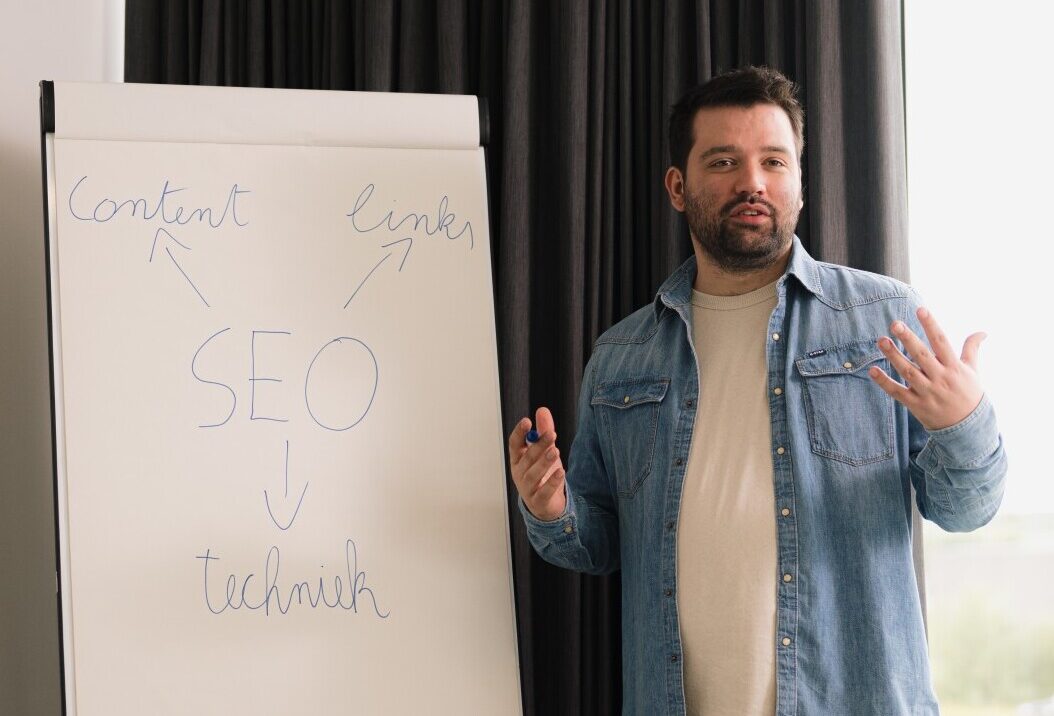 Mathias legt de drie aspecten van seo uit: content, techniek en autoriteit aan een whiteboard.